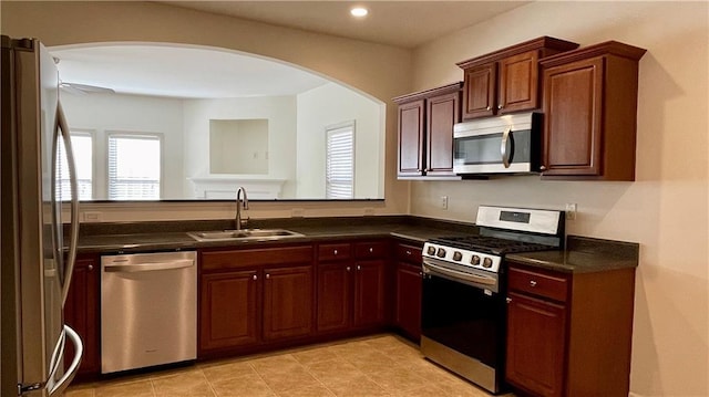 kitchen with stainless steel appliances, dark countertops, a sink, and recessed lighting