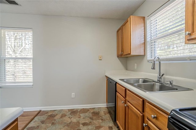 kitchen with black dishwasher, light countertops, visible vents, a sink, and baseboards