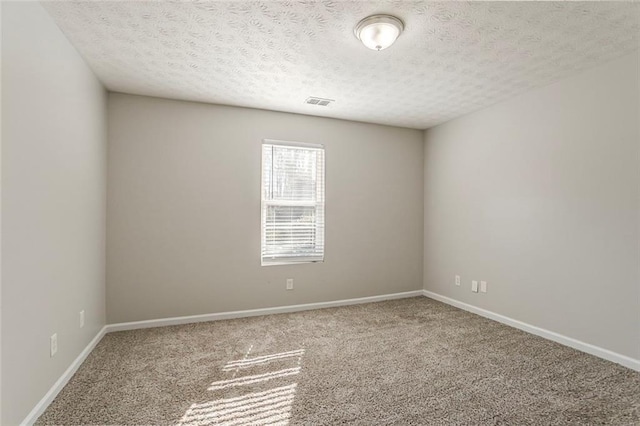 carpeted spare room with a textured ceiling and baseboards