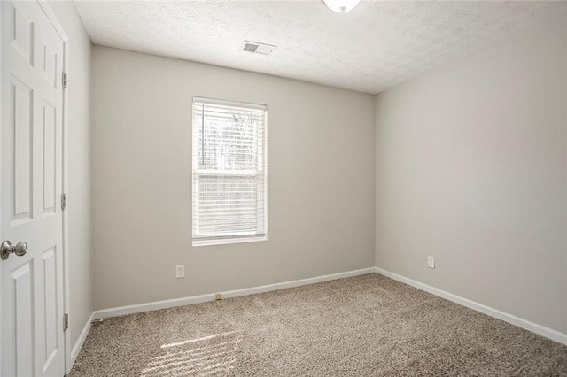 carpeted empty room with baseboards, visible vents, and a textured ceiling