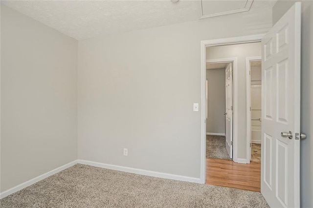 carpeted spare room with a textured ceiling and baseboards