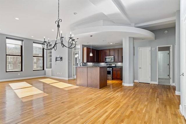 kitchen with open floor plan, light wood-style flooring, a notable chandelier, and stainless steel appliances