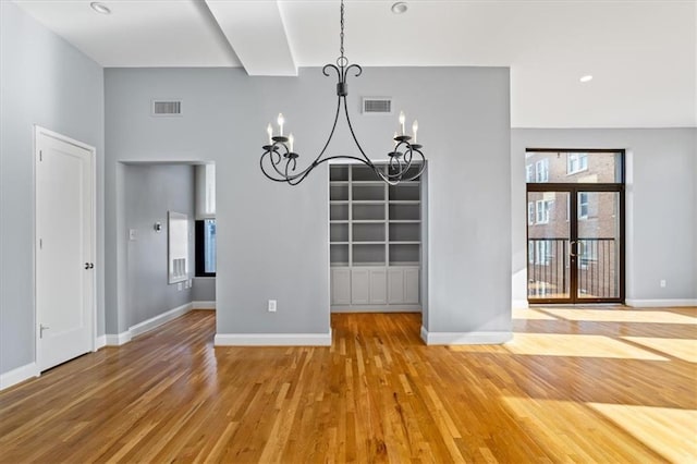 unfurnished dining area with light wood-style floors, baseboards, visible vents, and a notable chandelier