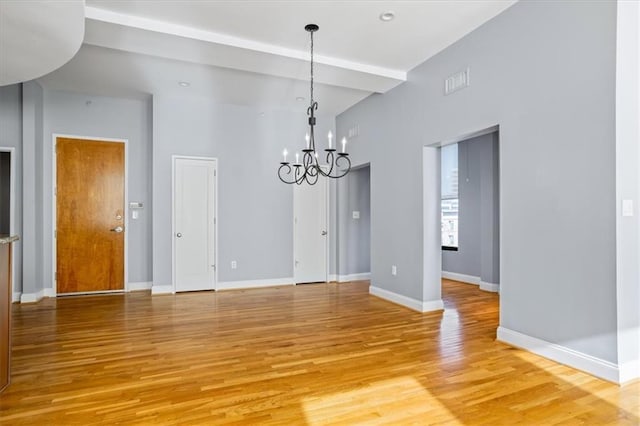 unfurnished dining area featuring baseboards, visible vents, light wood-style flooring, and a chandelier