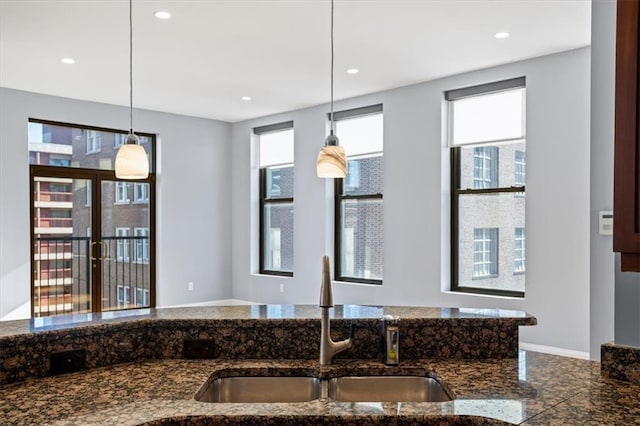 kitchen featuring a sink, dark stone counters, recessed lighting, and decorative light fixtures