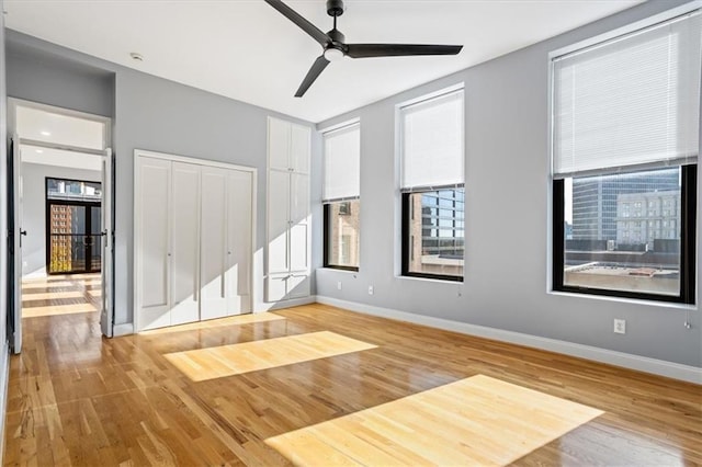 interior space with a ceiling fan, baseboards, and wood finished floors