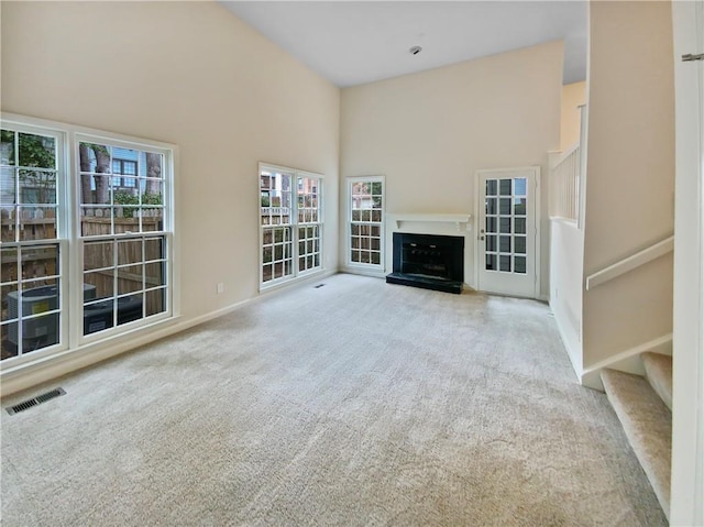 unfurnished living room featuring a towering ceiling and light colored carpet