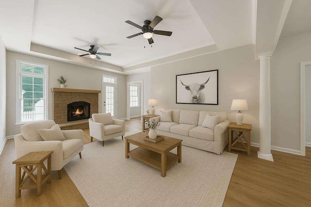 1460 Bakers Bridge Rd, Douglasville, GA 30134 - living area featuring a tray ceiling, baseboards, light wood-style flooring, a ceiling fan, and decorative columns