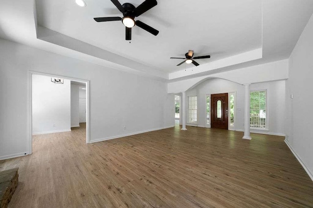 1460 Bakers Bridge Rd, Douglasville, GA 30134 - unfurnished living room with decorative columns, a tray ceiling, a ceiling fan, and wood finished floors