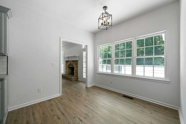 1460 Bakers Bridge Rd, Douglasville, GA 30134 - unfurnished dining area with wood finished floors, baseboards, a chandelier, and a stone fireplace