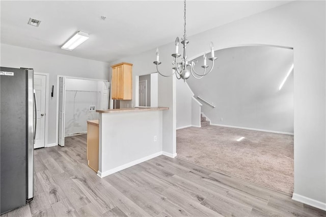 181 Ridgemont Rd, Canton, GA 30114 - kitchen with freestanding refrigerator, light brown cabinetry, a chandelier, arched walkways, and light wood-style flooring