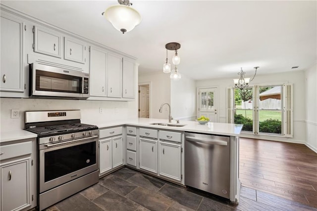 kitchen featuring decorative light fixtures, light countertops, appliances with stainless steel finishes, a sink, and a peninsula