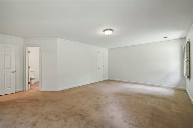 spare room with light colored carpet, crown molding, and baseboards