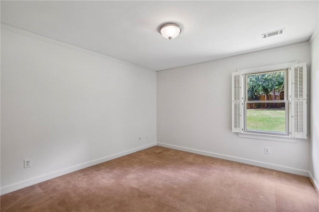 spare room featuring carpet floors, ornamental molding, visible vents, and baseboards