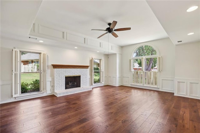 unfurnished living room featuring a ceiling fan, dark wood-style flooring, a fireplace, and a decorative wall