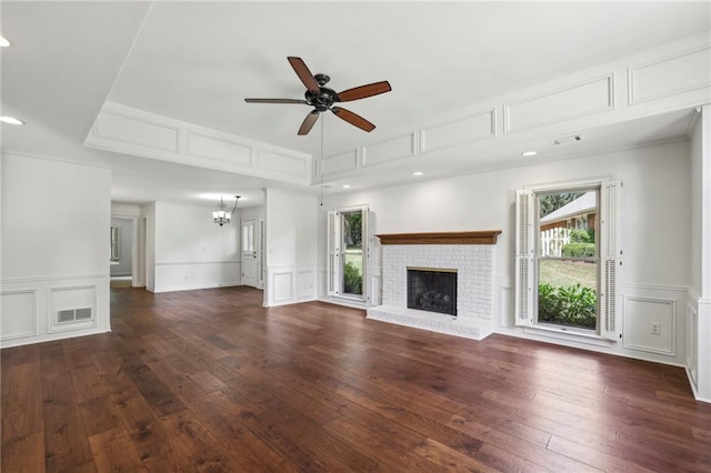 unfurnished living room with a fireplace, a decorative wall, and ceiling fan with notable chandelier