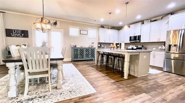 109 Red Fox Dr, Dallas, GA 30157 - kitchen with stainless steel appliances, a center island with sink, ornamental molding, wood finished floors, and white cabinetry