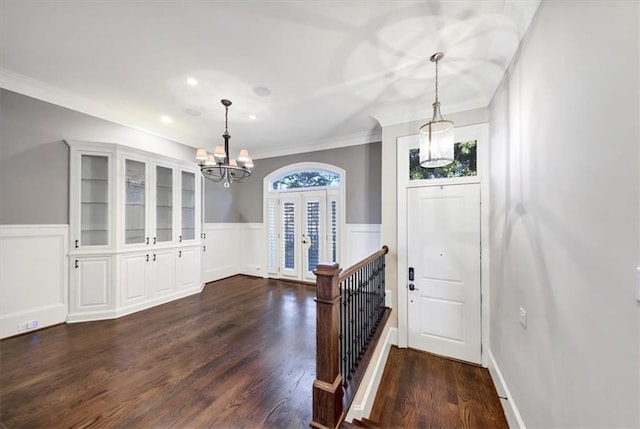 foyer featuring dark wood-type flooring, ornamental molding, and a chandelier