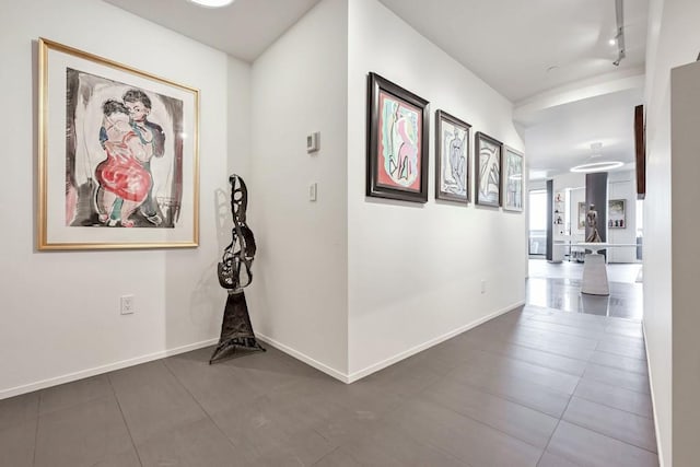 hall with dark tile patterned floors and track lighting