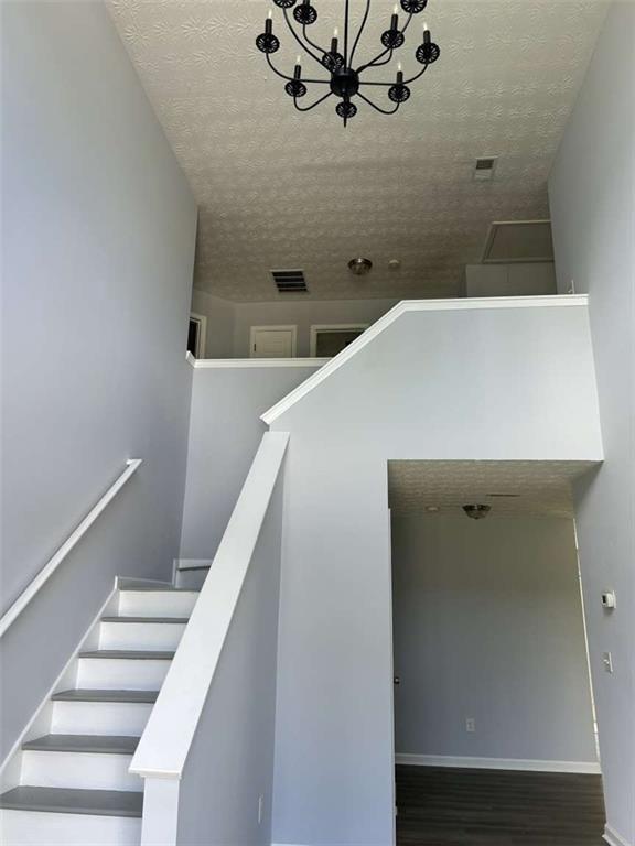 stairs with hardwood / wood-style flooring, a notable chandelier, and a towering ceiling