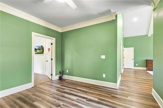 spare room featuring baseboards, visible vents, wood finished floors, and ornamental molding