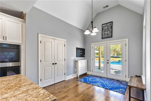 doorway with high vaulted ceiling, dark wood-style flooring, visible vents, baseboards, and french doors