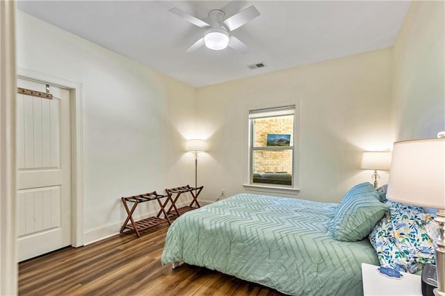 bedroom featuring a ceiling fan, dark wood-style flooring, visible vents, and baseboards