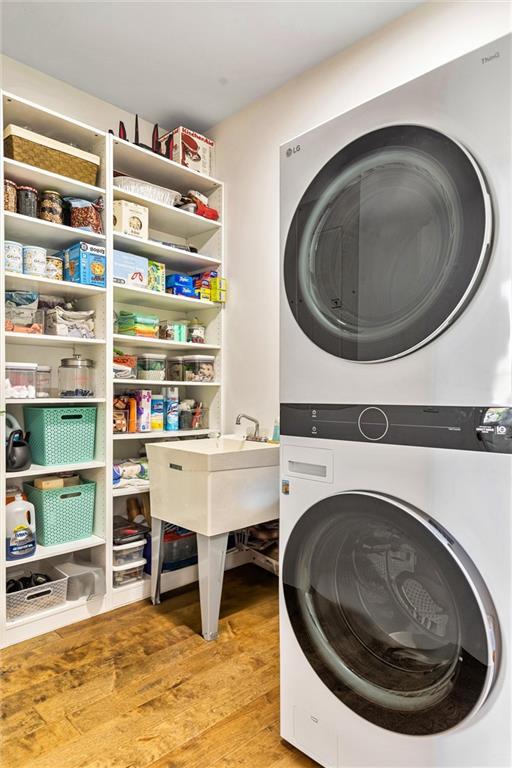 laundry room with light wood-style flooring and stacked washer / drying machine