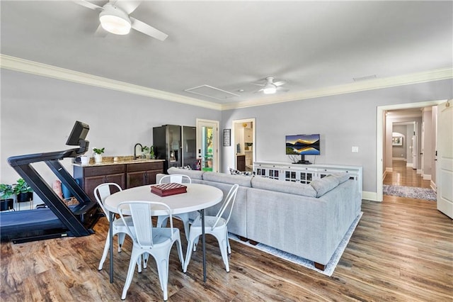 dining space featuring crown molding, attic access, ceiling fan, and wood finished floors