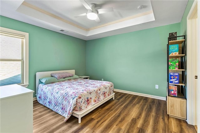 bedroom featuring baseboards, visible vents, a tray ceiling, and dark wood-type flooring