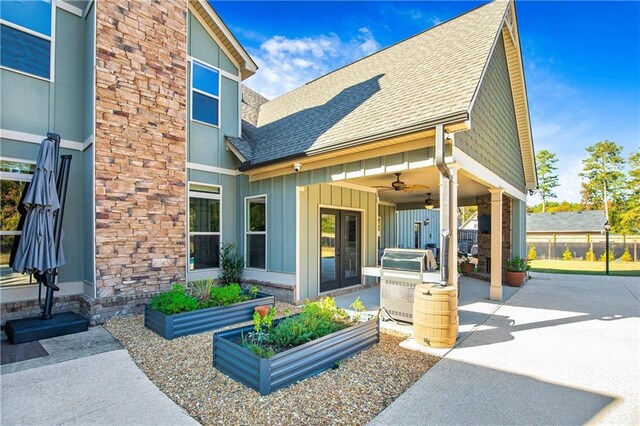 view of front facade with a shingled roof, ceiling fan, fence, a patio area, and board and batten siding