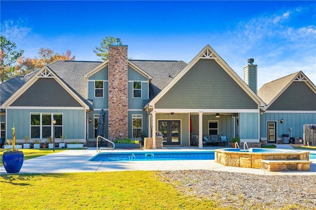 rear view of house with ceiling fan, a patio, french doors, board and batten siding, and a chimney