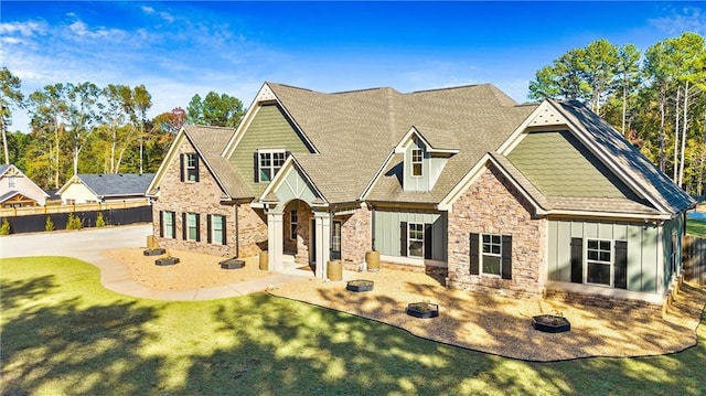 craftsman-style house with fence, a front yard, stone siding, board and batten siding, and a patio area