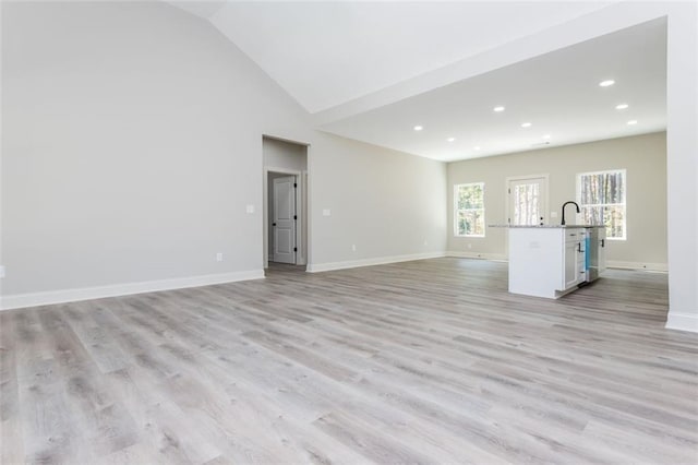 unfurnished living room featuring recessed lighting, light wood-style floors, baseboards, and high vaulted ceiling