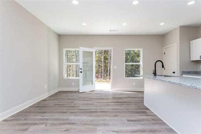 interior space featuring baseboards, visible vents, recessed lighting, a sink, and light wood-type flooring