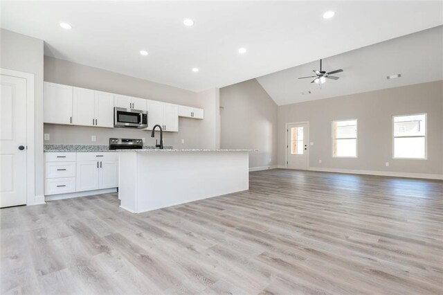 kitchen featuring an island with sink, a sink, stainless steel appliances, white cabinets, and open floor plan