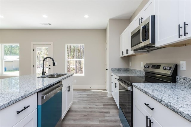 kitchen featuring light stone counters, recessed lighting, a sink, stainless steel appliances, and white cabinets