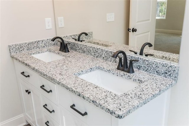 full bathroom with double vanity, baseboards, and a sink