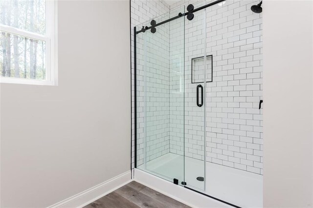 bathroom featuring a shower stall, wood finished floors, and baseboards