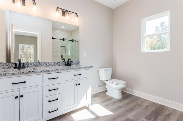 bathroom with a sink, wood finished floors, a shower stall, double vanity, and baseboards