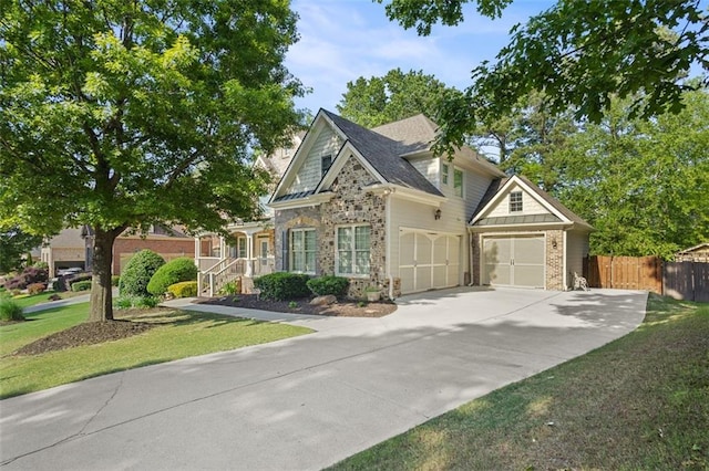 craftsman-style home with a front lawn, fence, stone siding, brick siding, and concrete driveway