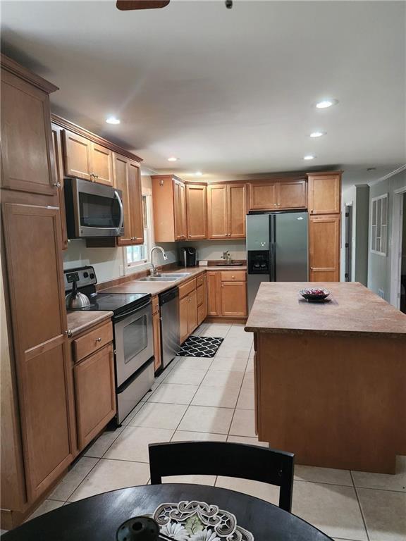 kitchen featuring light tile patterned floors, appliances with stainless steel finishes, sink, and a center island