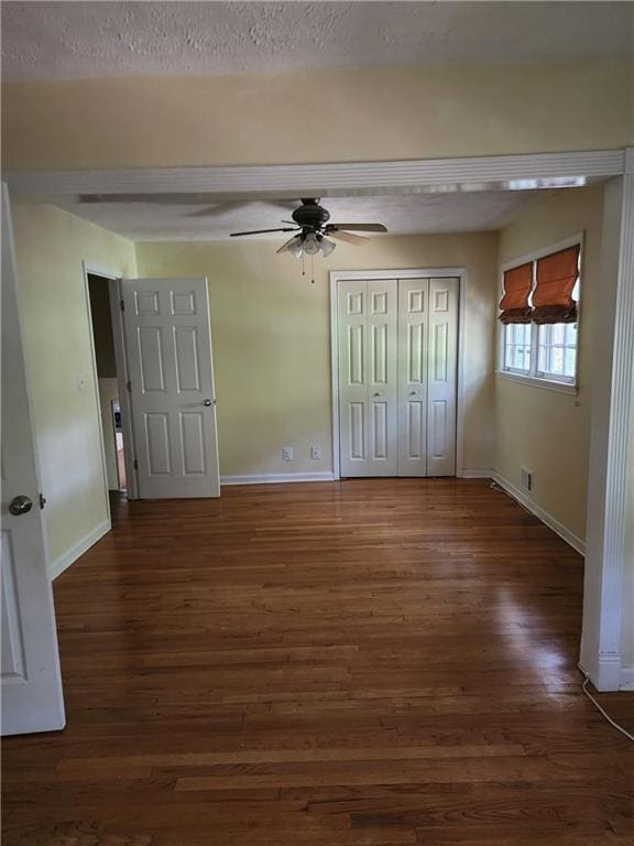 unfurnished bedroom with ceiling fan, a textured ceiling, and dark hardwood / wood-style flooring