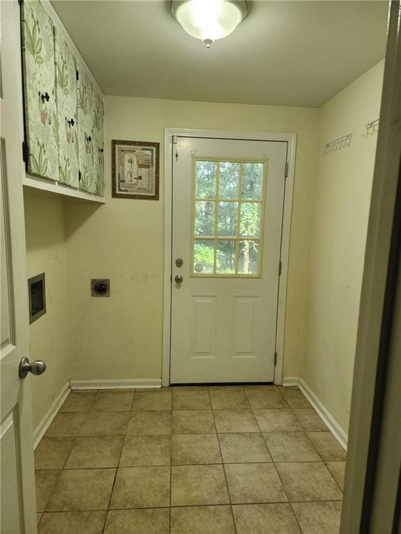 laundry area featuring cabinets, light tile patterned flooring, and electric dryer hookup