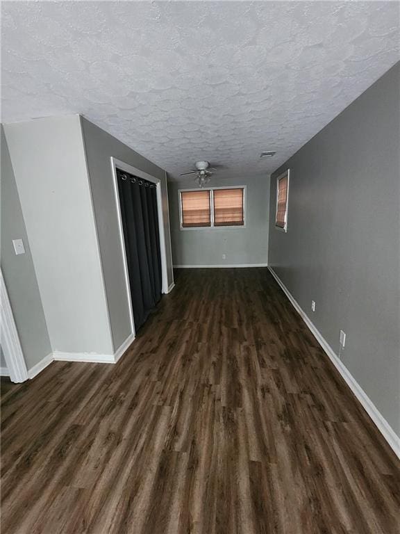 empty room featuring dark wood-type flooring, ceiling fan, and a textured ceiling