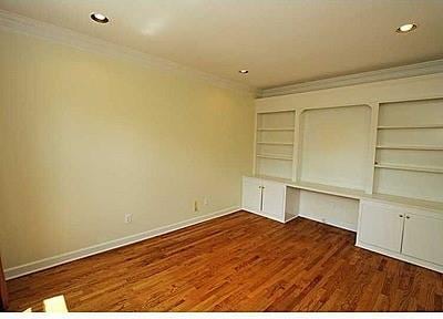 spare room featuring built in shelves, ornamental molding, and dark hardwood / wood-style flooring