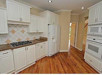 kitchen with white appliances, white cabinets, backsplash, and dark hardwood / wood-style floors