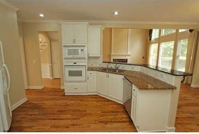 kitchen featuring hardwood / wood-style floors, white appliances, white cabinets, dark stone countertops, and sink