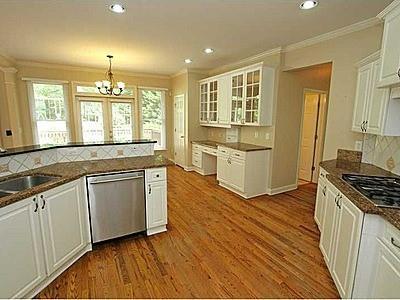 kitchen with an inviting chandelier, tasteful backsplash, white cabinets, a healthy amount of sunlight, and dishwasher