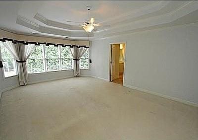 unfurnished room with ceiling fan, ornamental molding, a tray ceiling, and light colored carpet